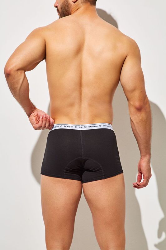Back view of man wearing black Intymen boxer briefs with white logo waistband.