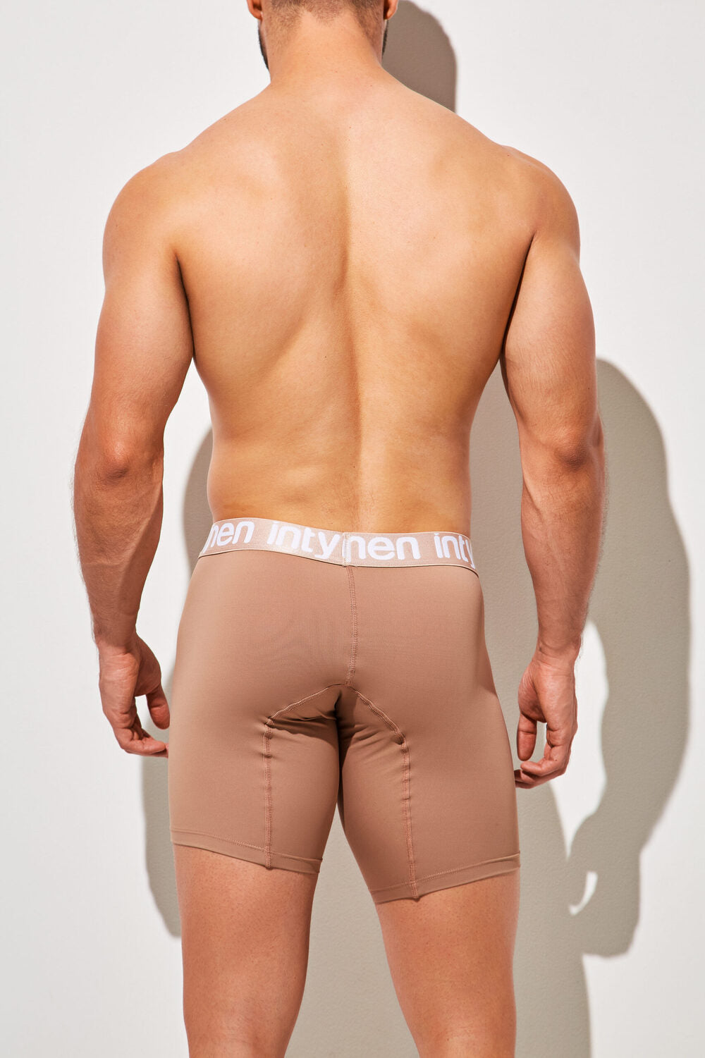 Back view of man wearing mocha Intymen long boxer briefs with white logo waistband.
