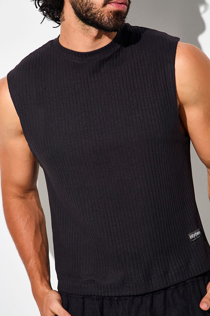 Close-up of a man wearing a sleeveless black ribbed top.
