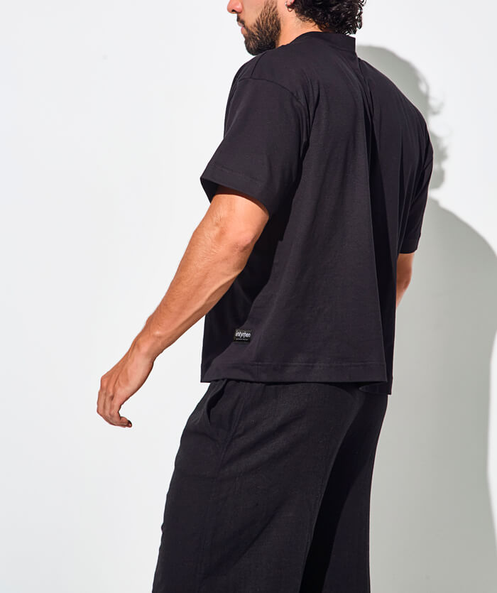 Back view of a man wearing a black t-shirt and black pants.