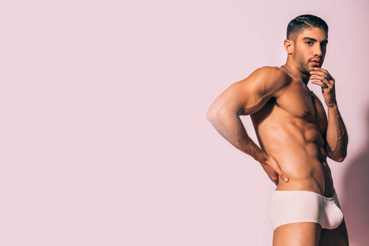 5 Important lessons Bikini taught us - Man posing in light-colored underwear against a pink background.