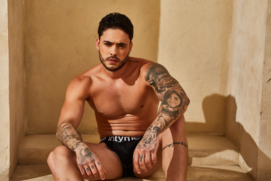 Are You Sure? You Are Wearing Right Men’s Underwear? - Man with tattoos posing in black underwear while sitting.