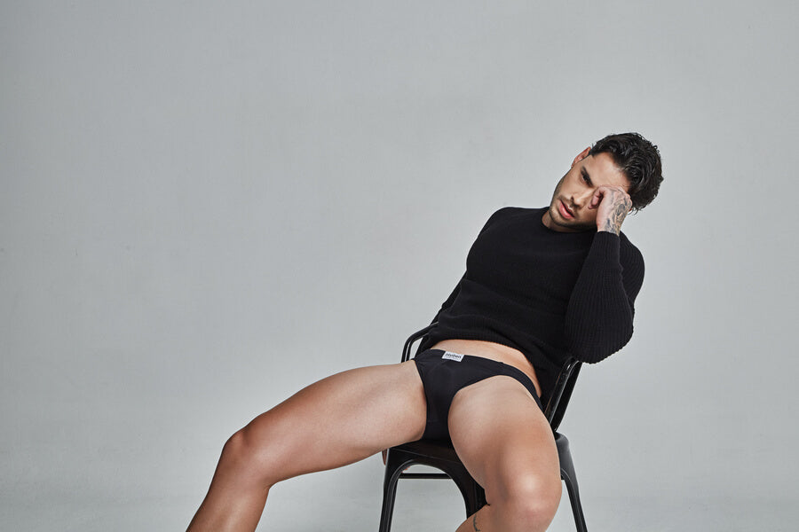 Showcase Your Machismo With Intymen Underwear For Men -  Man in black sweater and black briefs sitting in a chair