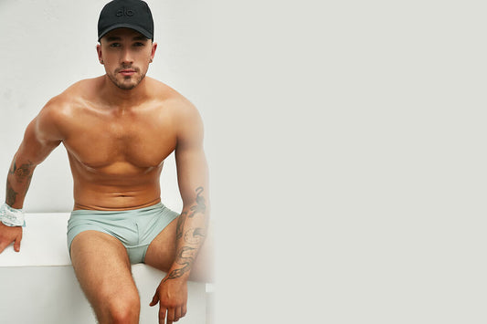 Why Should You Buy the New Arrivals by Intymen? - Man sitting and posing in light mint underwear and a black cap.
